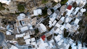 A small city on the island in Greece from the drone. Birds view over the white houses near the Mediterranean Sea on the sunset.