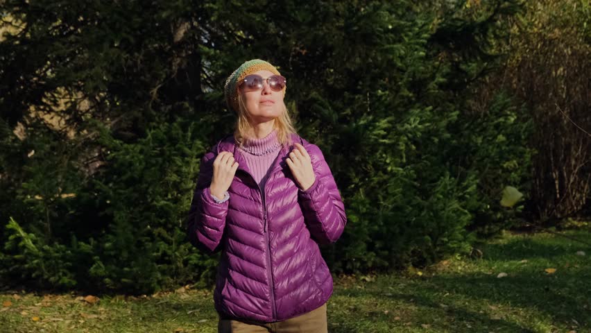 Happy adult woman enjoying walk in the sunny spring parkland. Female blonde inhaling fresh air, reducing stress while walking in the forest.