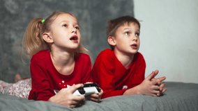 Children are playing a video game console. The younger sister holds the gamepad and the paddle laughs, the older brother prompts and comments. A lively dynamic hand held shot from a low angle.