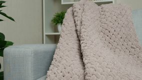 Knitted large plaid blanket in dusty rose light grayish-red color on the sofa.