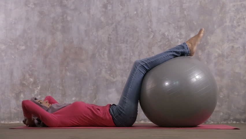 portrait of beautiful hijab sporty woman doing sit up using swiss ball