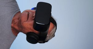 Vertical clip. Asian old man having fun playing games while wearing virtual reality glasses.