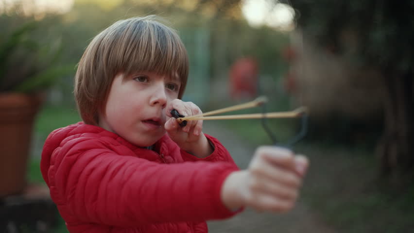 7 year old boy enjoys playing with the slingshot outdoors