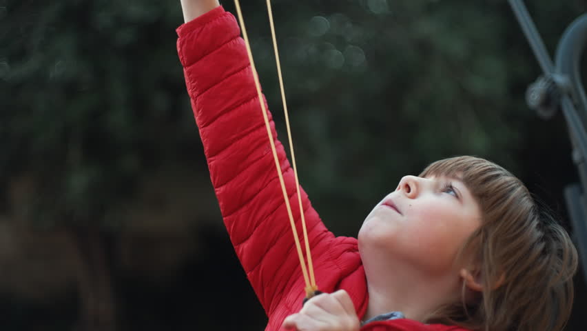 7 year old boy enjoys playing with the slingshot outdoors