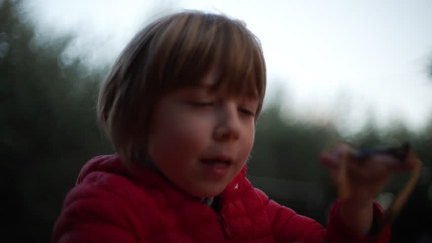 7 year old boy enjoys playing with the slingshot outdoors