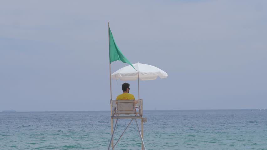 A lifeboat station on the beach in close-up. A man lifeguard sitting and looking for people swimining in sea. Safety in open waters, safe vacation during storm