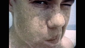 Young man funny portrait on sea backdrop, close up. Teenage boy face, zoom in eye macro. Caucasian male teen look in camera. Archival 4k vintage footage. Overscan retro film. Obsolete 1980s video