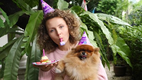 Happy Young Woman Celebrating Birthday With Her Dog In Hats With Cake Outdoors. 4K. 