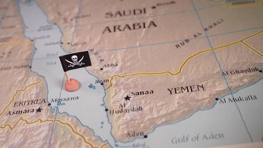 Hand placing pins adorned with the flags of the USA and Iran surrounding a pirate insignia onto a map of the Red Sea region. It symbolically represents the intricate geopolitical dynamics and Royalty-Free Stock Footage #3414751807