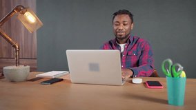 Positive friendly african american man having work meeting online on laptop sitting in workplace in home office. Smiling guy talking with coworkers in video chat, call. Remote, distant job concept.