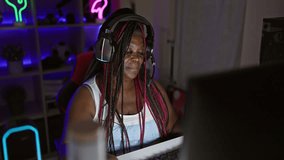 African american woman streamer playing video game with winner expression at gaming room