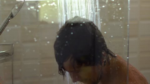 Portrate of a sad man in a shower. Focus on a man