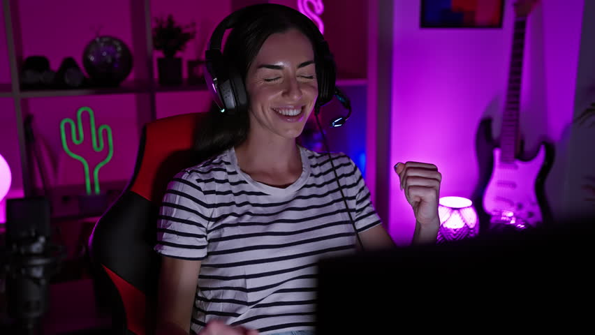 Incredible night of gaming fun, young, beautiful hispanic woman streamer celebrates winning gaming while dancing in gaming room!