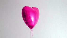 One beautiful big pink heart shaped balloon with ribbon isolated on a white background. Birthday party gift. Floating object. Inflatable ball by helium gas. Valentines day gift. Love symbol. 4k. - Powered by Shutterstock - Get 15% off with code: PIKWIZARD15