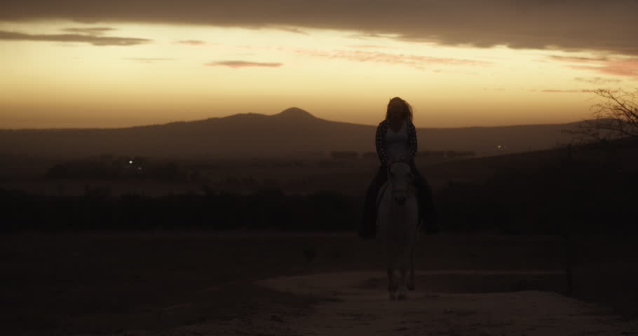 Woman, cowgirl and horse ride at sunset in countryside for travel or transport in nature. Female person or farmer riding on animal for outdoor adventure, journey or trip with silhouette at night