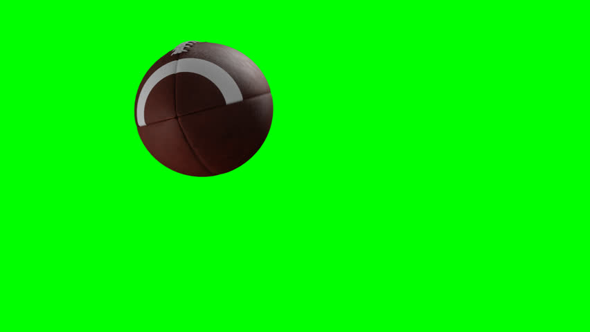 An American football spiraling through the air in slow motion across the frame on a transparent  