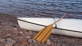 bow of expedition canoe with a wooden paddle on a rocky lake shore - Horsetooth Reservoir in northern Colorado - Powered by Shutterstock - Get 15% off with code: PIKWIZARD15