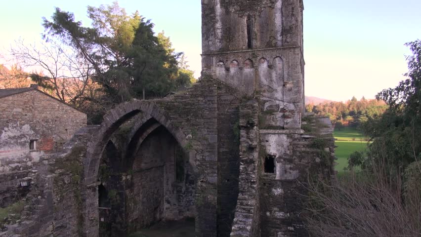 aerial view of an ancient abandoned church with tower and golf green field on back 