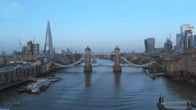 Drone shot over the Tower Bridge in London United Kingdom, on a sunny day with no clouds and skyline on a background. Sunrise shot in hi quality 4K footage. 