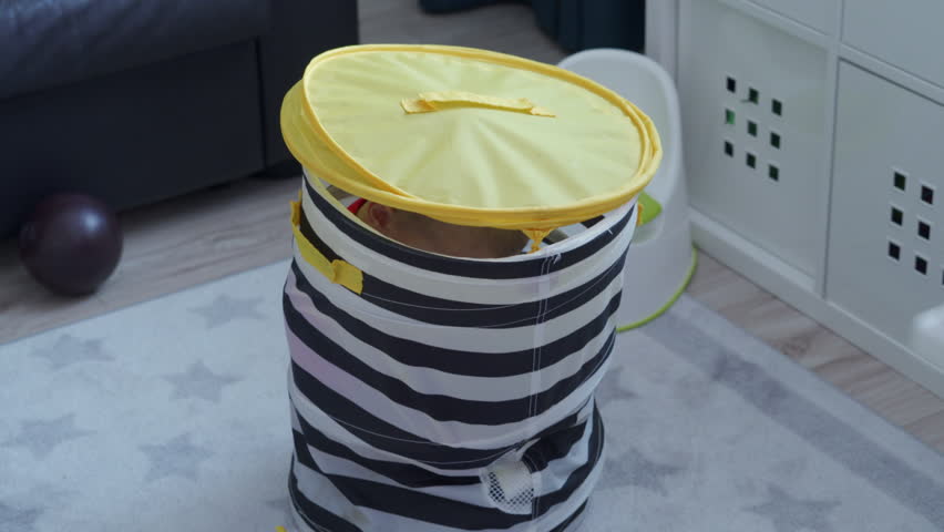 3-year-old child little boy is hiding in toy storage bag with lid