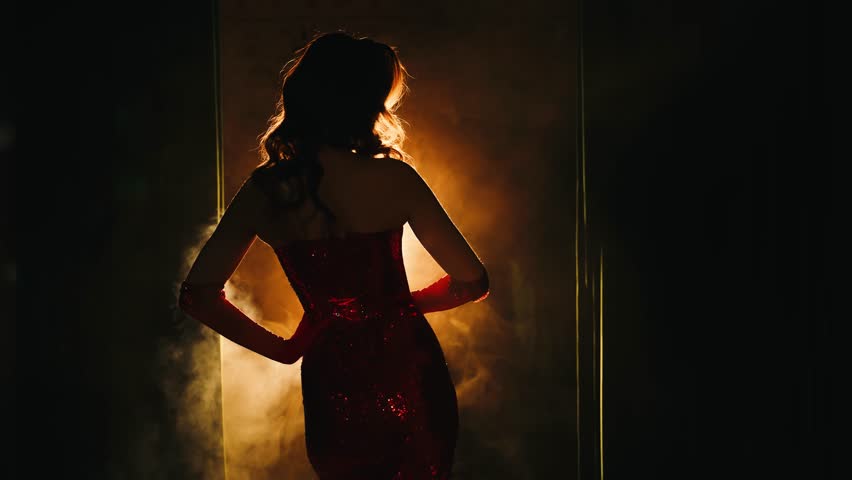 Sexy woman retro lady smoker holding cigarette mouthpiece in hands back rear view. art portrait glamour dark silhouette girl red shiny dress. hair 20s 30s old style. Black burning room full smoke. 4k