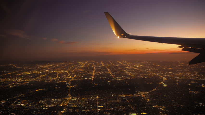 Airplane Jet plane prepare to landing in Los Angeles LAX airport. Porthole view with wing on sunset time. Slow motion