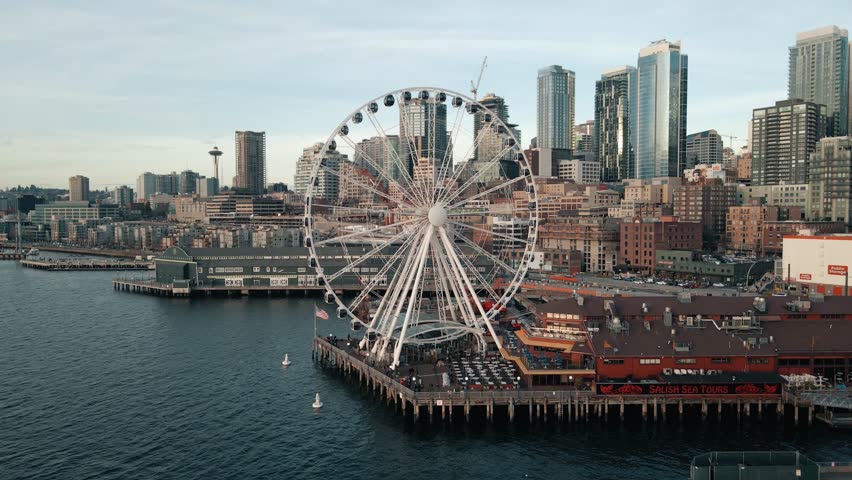 Drone flyover above Seattle ferris wheel to reveal dense urban buildings and skyline at sunset Royalty-Free Stock Footage #3415204209