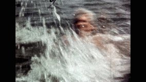 Man splashing in sea water, close up. Happy vacationing man active swim, floundering in ocean. Swimming joy in sea. Beach recreation in vacation. Vintage color film. Recreation archive. Retro 1980s