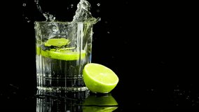 A slice of lime falls into a glass of water. Slow motion. Isolated on black background. - Powered by Shutterstock - Get 15% off with code: PIKWIZARD15