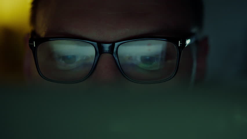An IT specialist's glasses reflect lines of code flashing on an office monitor throughout the night. Focused programmer working hard on laptop laptop interacting with advanced software Royalty-Free Stock Footage #3415442693