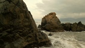 The waves are hitting the rocks. Dawn on the rocky shore. Slow motion video. Morning at the Pig Cave, near Nha Trang in Vietnam. The South China Sea.