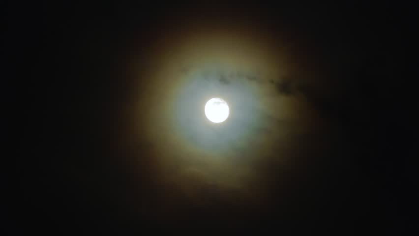 Full moon in the night sky. The corona is a light optical phenomenon in the form of colored clouds around the Moon on a dark, cloudy night Royalty-Free Stock Footage #3415498275