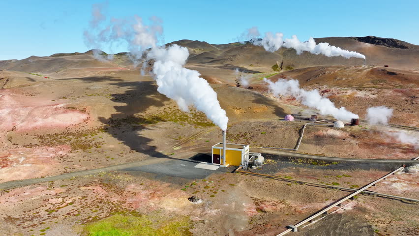 Modern Geothermal Energy Power Plant Working, Located in a Picturesque Volcanic Landscape in Iceland. Hot White Steam Smoke is Coming From Pipes. Renewable Green Energy Aerial View. High quality 4k