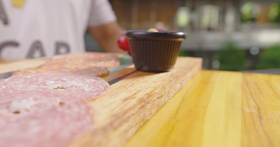 Preparation of a delicious starter of ham, cheese, red grapes, purple grapes, cherry tomato, jelly, fresh olives. Delicious board of hams and cheeses with fruit to share at a table gourmet party