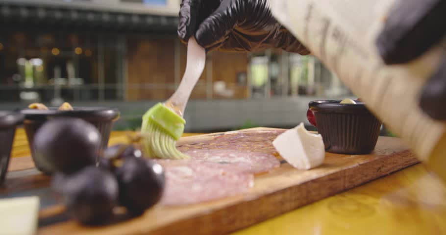 Preparation of a delicious starter of ham, cheese, red grapes, purple grapes, cherry tomato, jelly, fresh olives. Delicious board of hams and cheeses with fruit to share at a table gourmet party