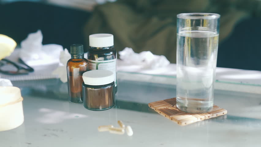 Medicine, glass of water and pills on table in home for health, wellness or care. Drugs, pharmaceutical capsule or tablet bottle on coaster with antibiotic, vitamin or medical prescription supplement