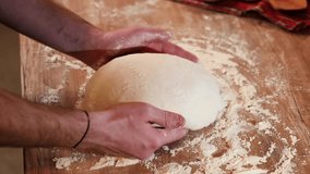 Shaping the sourdough. 4K video view from above with male hands while shaping a home made bread dough after the first rise. Home made fresh bread making process.