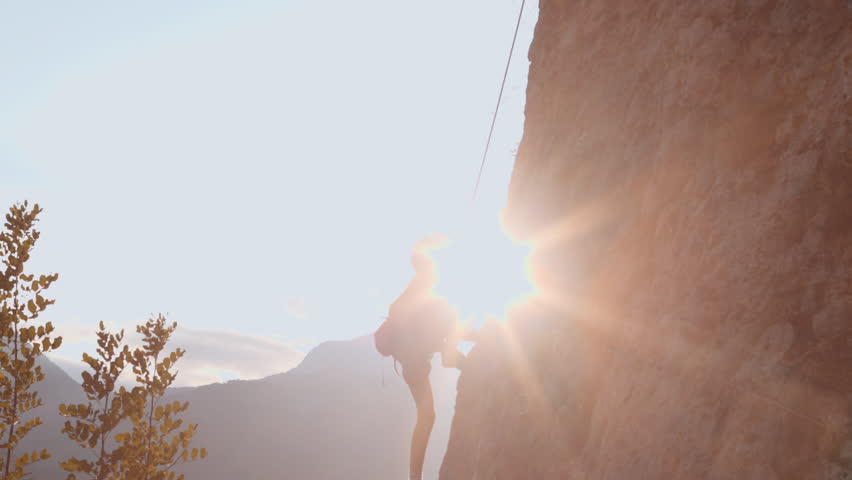 A child climbs a rock. A boy climbs a rock against the backdrop of mountains. Extreme hobby. Athletic child training to become strong.