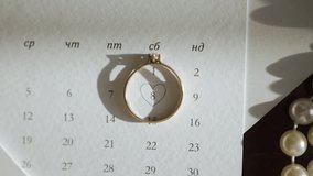 A golden ring poignantly casts a heart-shaped shadow upon a calendar page, with a significant date circled. The warm and gentle light accentuates the romantic symbolism of the scene - Powered by Shutterstock - Get 15% off with code: PIKWIZARD15