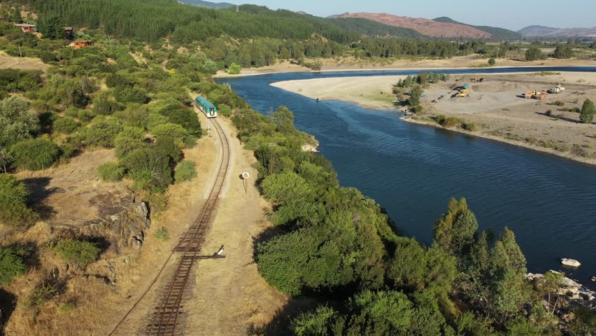 Train mooving through the forest, wineries alonong the banks of Maule river near Constitucion in Chile