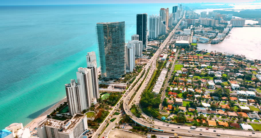 Drone descending above the multi-lane highway with multiple transport moving on. Beautiful Miami Beach, Florida, USA from top perspective.
