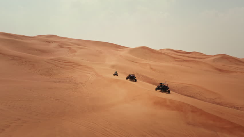 Tourists riding dune buggies in Dubai desert UAE, scenic aerial view