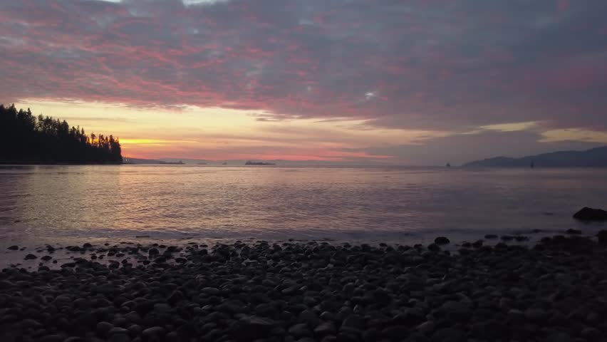 Beautiful view on a rocky shore overlooking the ocean during a vibrant sunset. Taken in North Vancouver, British Columbia, Canada. Pan Across, Low Angle