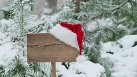 Santa hat on wooden road sign, nature background with pine trees and snowy forest. Concept of Christmas holiday and happy New Year. Winter nature. Signboard with red hat - Powered by Shutterstock - Get 15% off with code: PIKWIZARD15