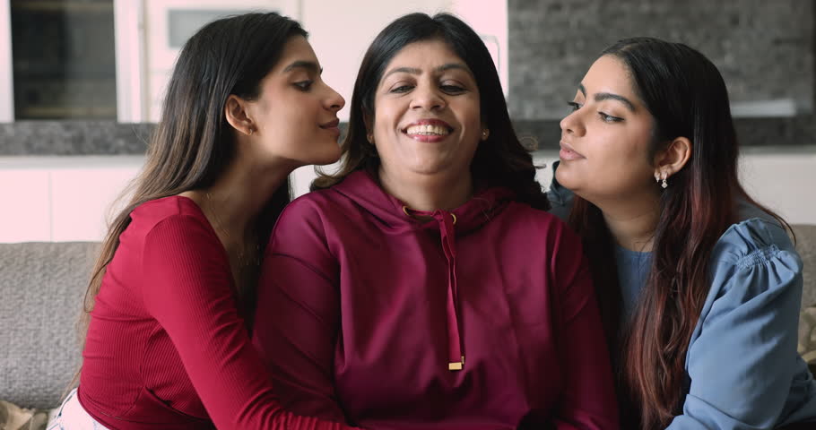 Multi-generational Indian relatives women hugging seated on sofa. Two loving young adult 20s daughter hugging, kissing their happy mature 55s mother express love, support, having strong family ties Royalty-Free Stock Footage #3416431467