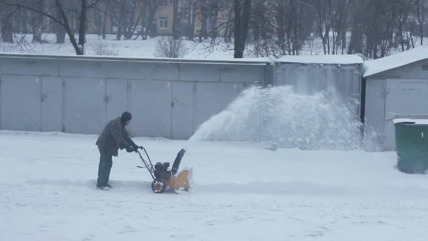 Man removes snow with a snow blower, Winter storm