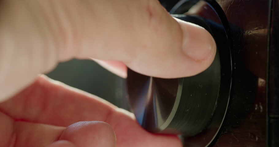 Adjusting the volume level on the receiver. Close-up of fingers turning the knob