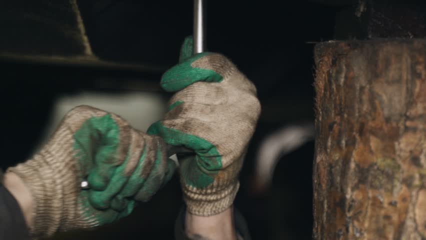 A mechanic tightens bolts with a wrench on the units and parts of a truck in a repair shop. Close-up.