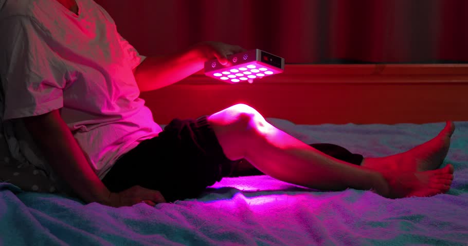 Closeup of treating sore leg with the red light therapy handheld device at home on the bed Royalty-Free Stock Footage #3416617357