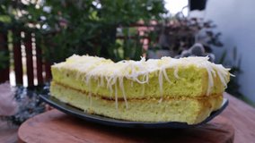 Classic Lemon Pound cake with grated cheese sprinkles and lemon sauce dripping on top on a wooden background. Two Layer of lemon cake with yellow syrup topping. Video 4k. Rotate table